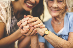 young woman holding elderly woman's hands