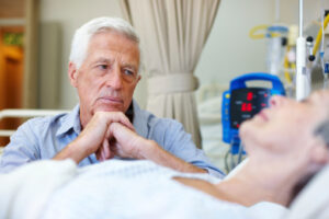 An elderly man looking concerned over his wife's condition while in the hospital