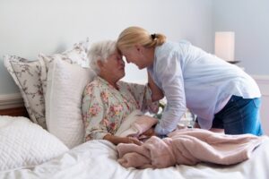 An older lady in bed while her daughter embraces her.