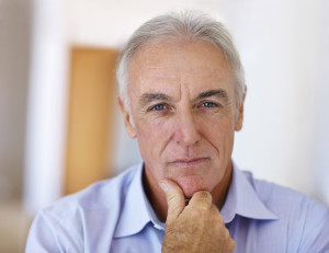 elderly man staring at the camera with his chin resting on his hand